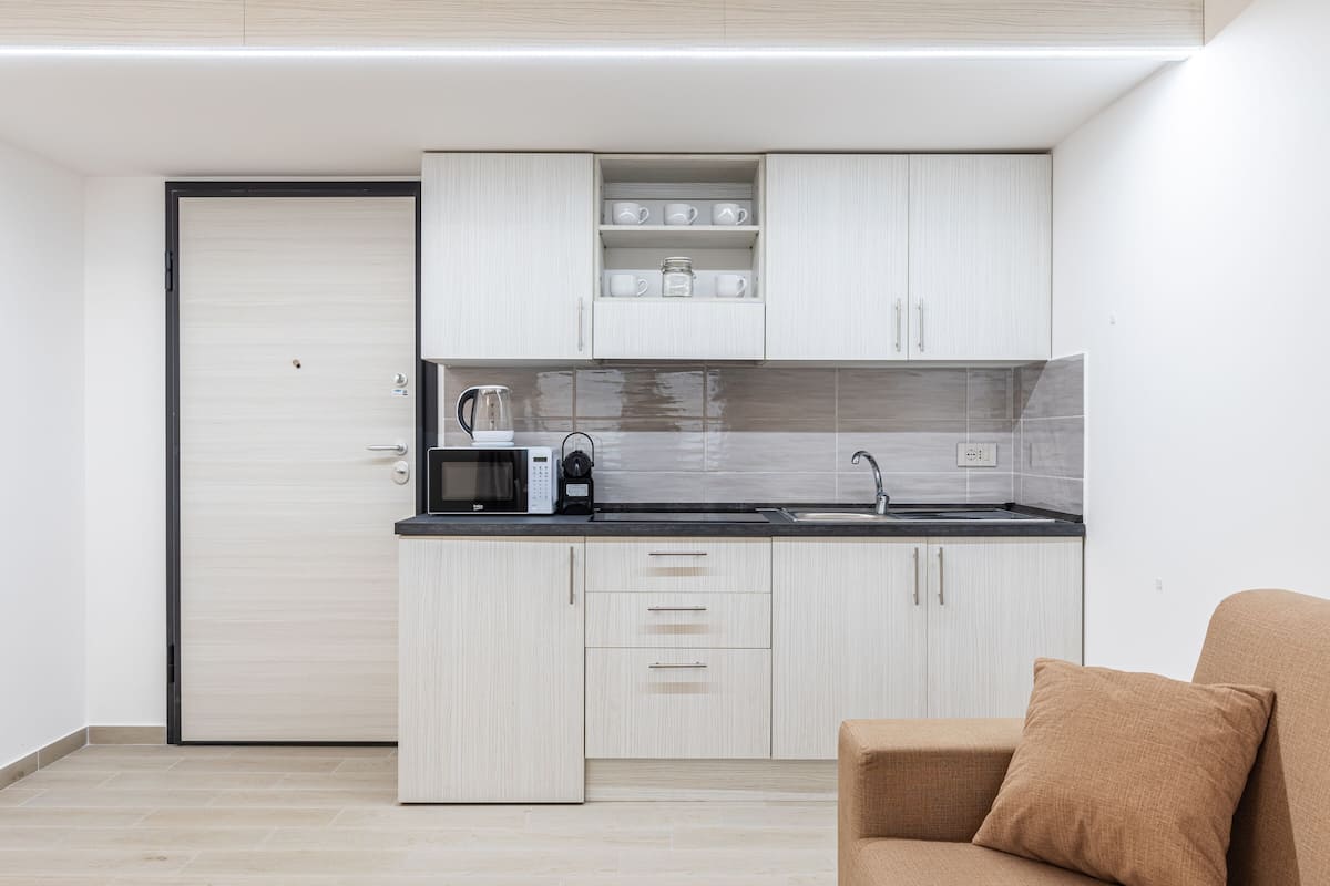 A modern kitchen with light wood cabinets, a black countertop, and a built-in microwave.