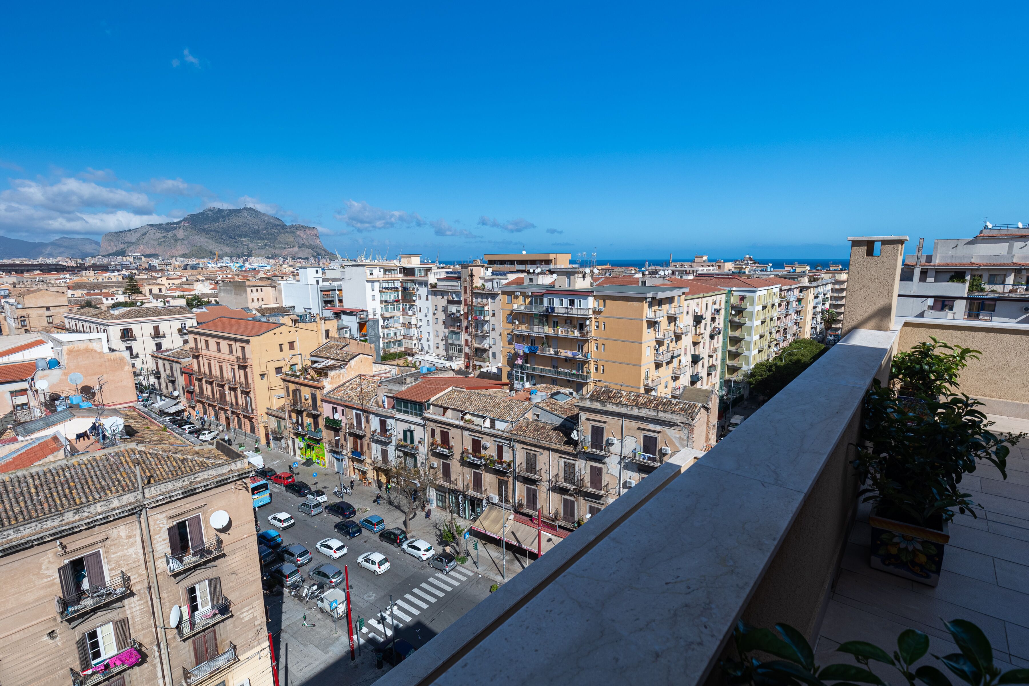 A cityscape with a view of the sea and mountains in the background.