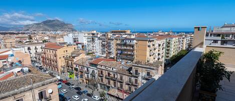 A cityscape with a view of the sea and mountains in the background.
