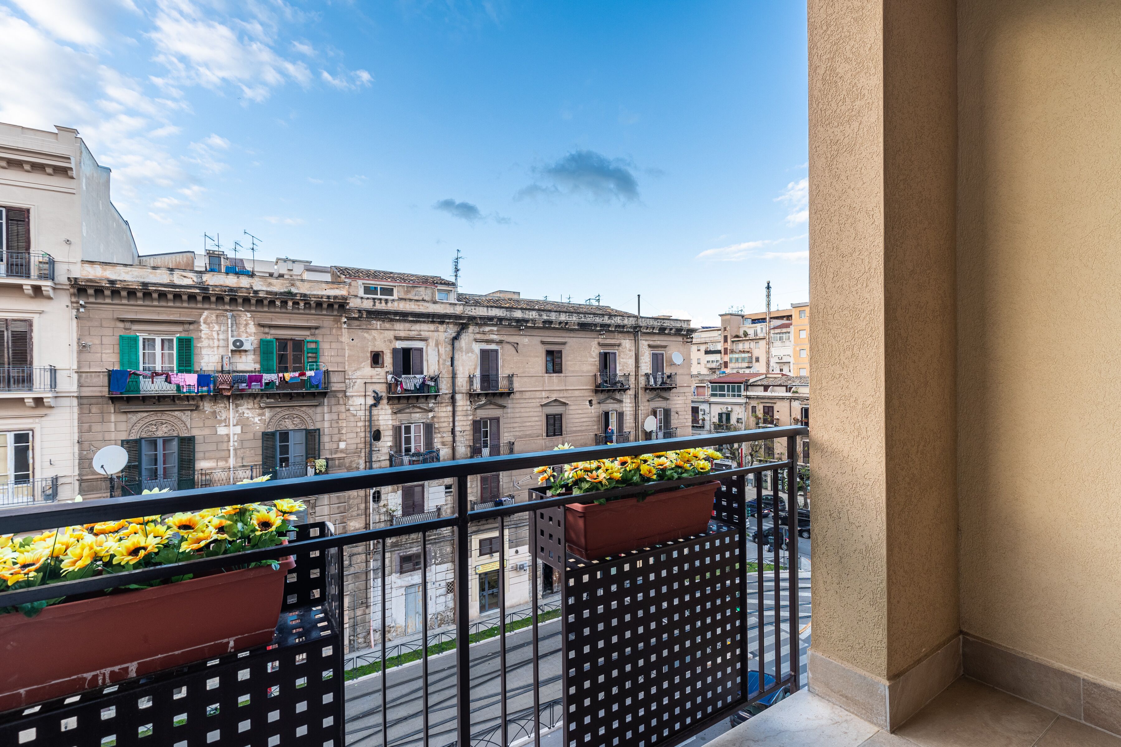 A balcony with flower boxes and a view of old buildings.
