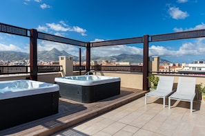 A rooftop terrace with two hot tubs and two lounge chairs, overlooking a cityscape and mountains. - Multisuite Palermo (Palermo)