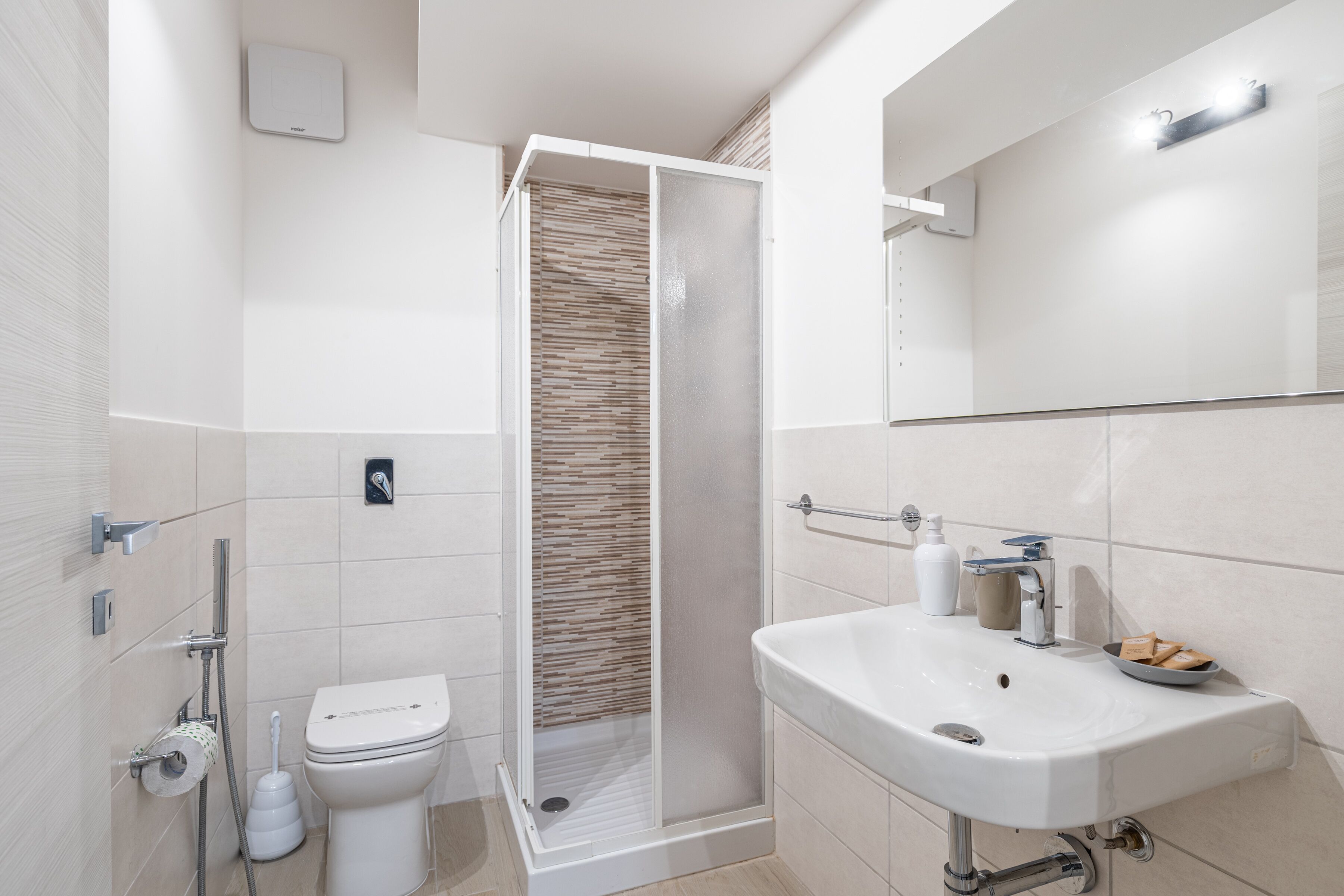Un baño moderno con cabina de ducha, inodoro y lavamanos.