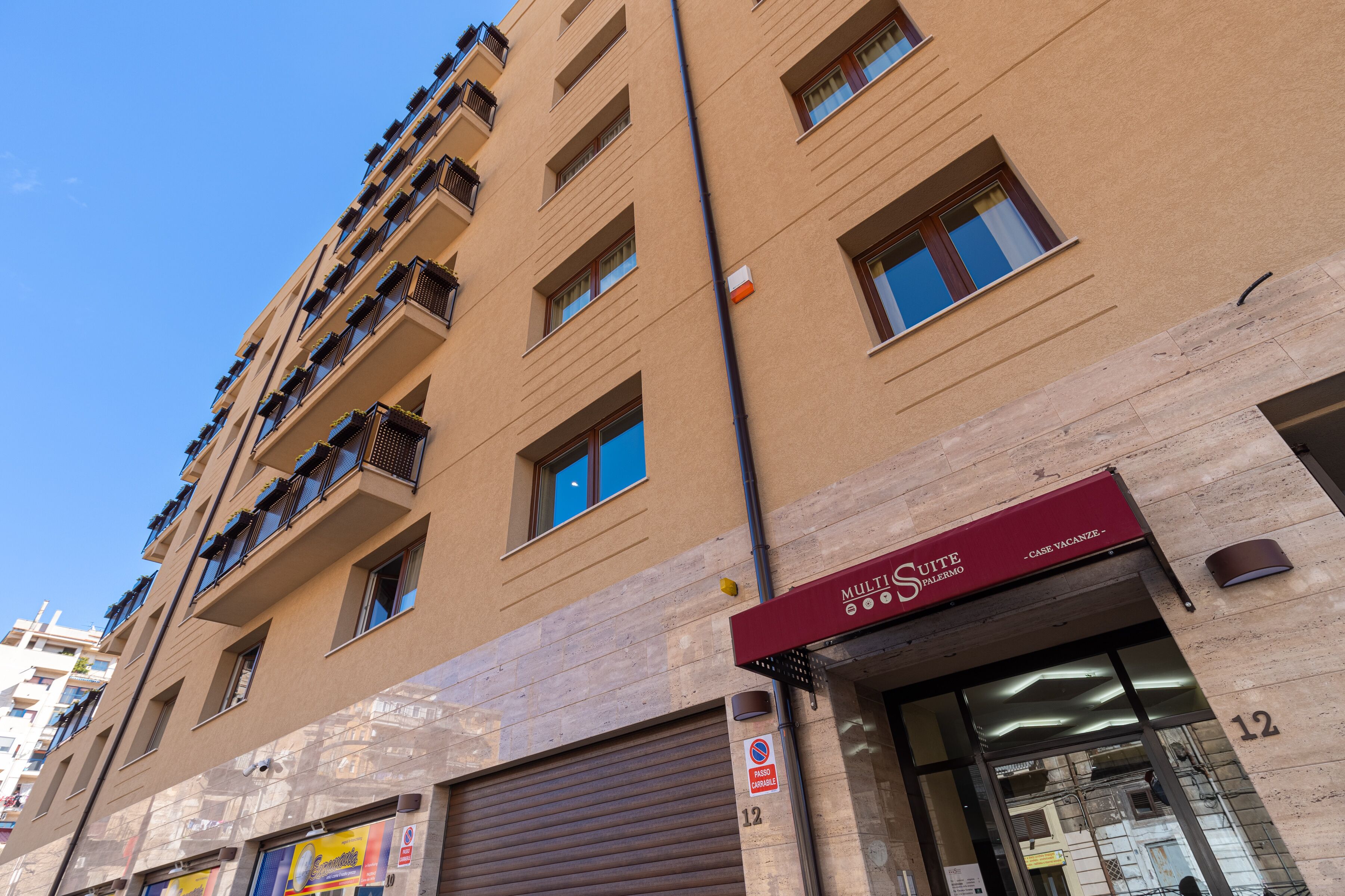 A multi-story building with a red awning labeled "MULTI Suite" and a visible number "12" on the facade.