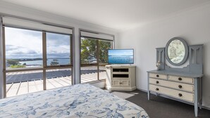 Quarto com uma janela grande, uma cama, uma TV e uma cômoda.