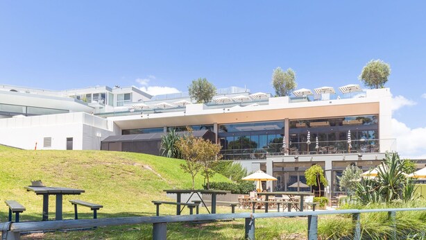 Un edificio moderno con techo plano, ventanas grandes y zonas de estar al aire libre.