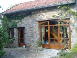 A stone building with a tiled roof, a wooden staircase, and a large glass door. - Charming stone house restored in English style (Arfeuilles)