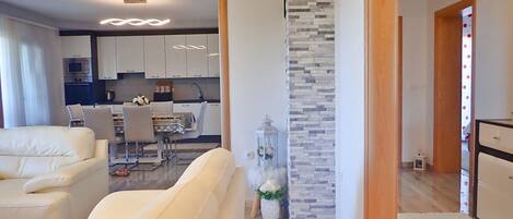 Una sala de estar moderna con un sofá, un comedor con una mesa y sillas, y una cocina al fondo.