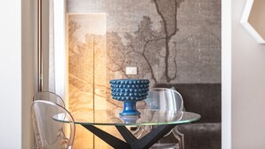 Un tavolo in vetro con un oggetto decorativo blu e sedie trasparenti in una stanza con una parete strutturata e una finestra.
