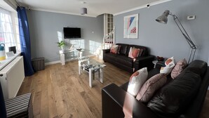 A modern living room with a sofa, coffee table, and a TV mounted on the wall. - Lancaster Close Serviced Accommodation (Bicester)