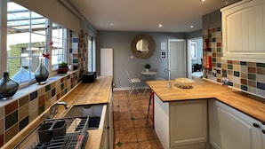 A modern kitchen with a large window, a wooden countertop, and a tiled backsplash. - Lancaster Close Serviced Accommodation (Bicester)