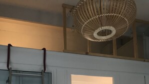A room with a white door, a ladder, a shelf with baskets, and a checkered floor.