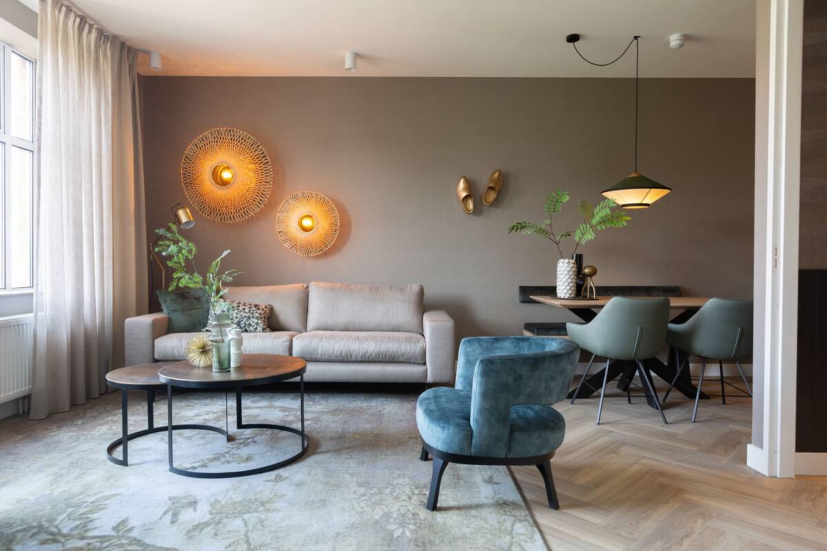 A modern living room with a sofa, two armchairs, a coffee table, and a dining area with chairs and a table.