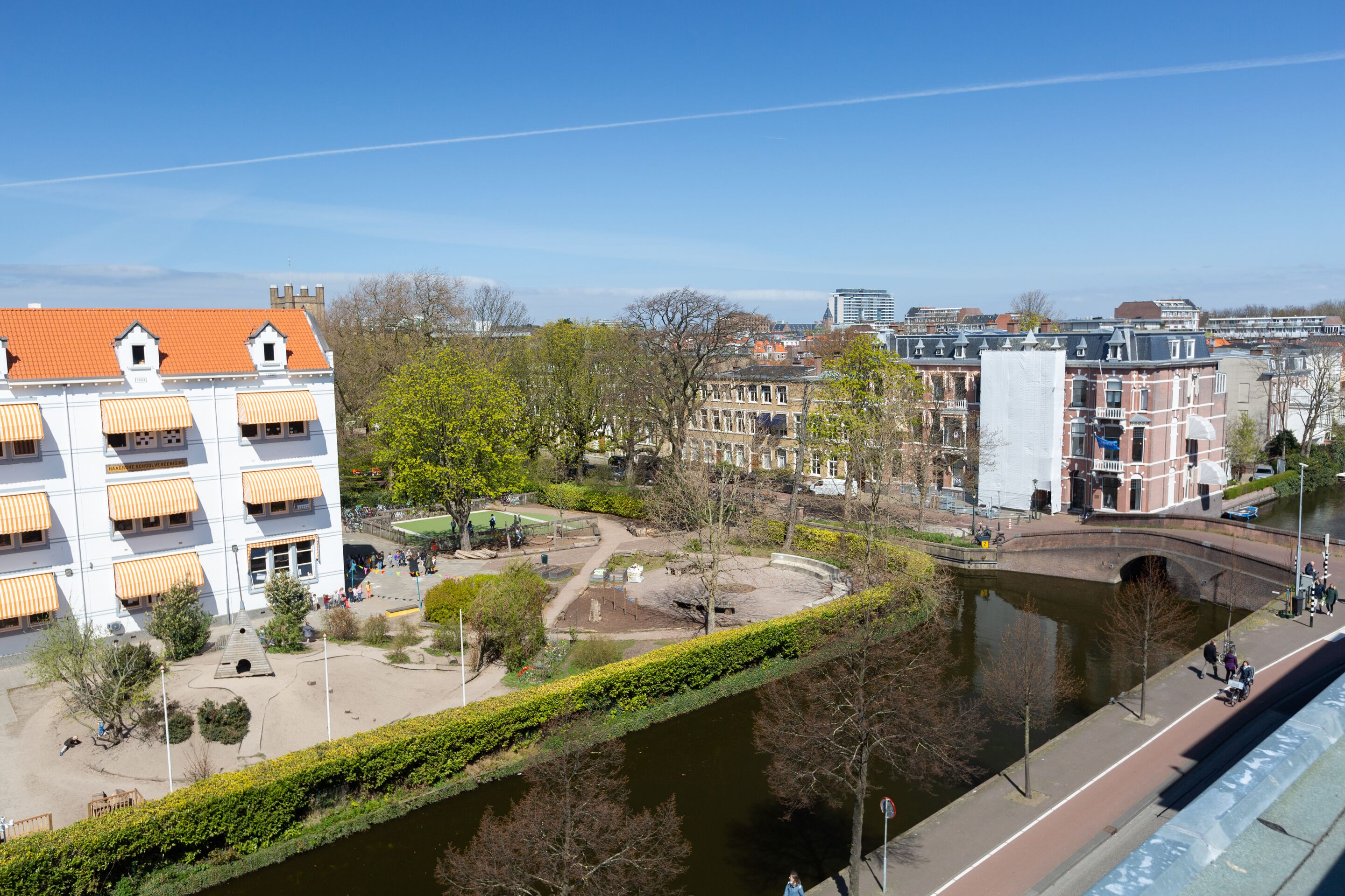 Une vue sur la ville, avec ses bâtiments historiques, un pont et un espace vert, depuis les rives d’une rivière.