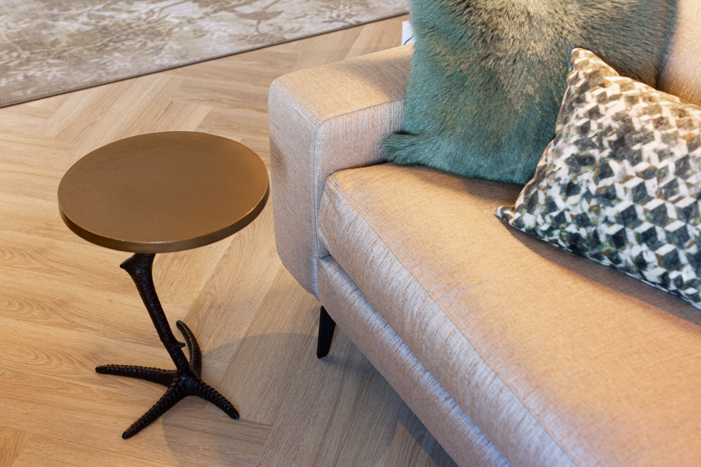 A round table with a star base, a sofa with patterned cushions, and a wooden floor.