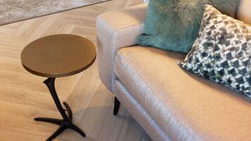 A round table with a star base, a sofa with patterned cushions, and a wooden floor.