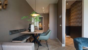 Een moderne eetruimte met een houten tafel, twee stoelen, een bankje en een plant in pot.