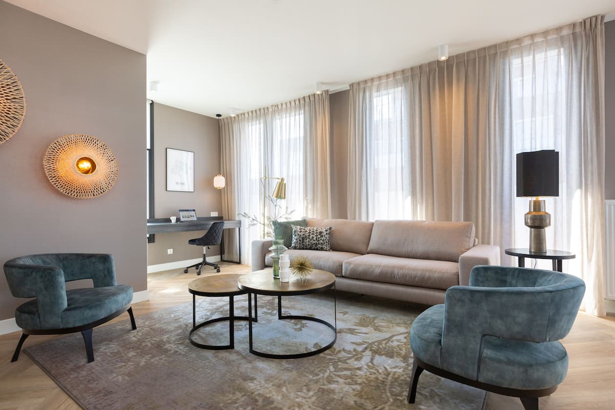 A modern living room with a sofa, two armchairs, a coffee table, and a desk with a chair.