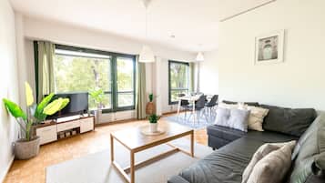 A modern living room with a sofa, coffee table, TV, and dining area.