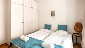 Un dormitorio con una cama, un armario, una lámpara de noche y una obra de arte colgada en la pared.