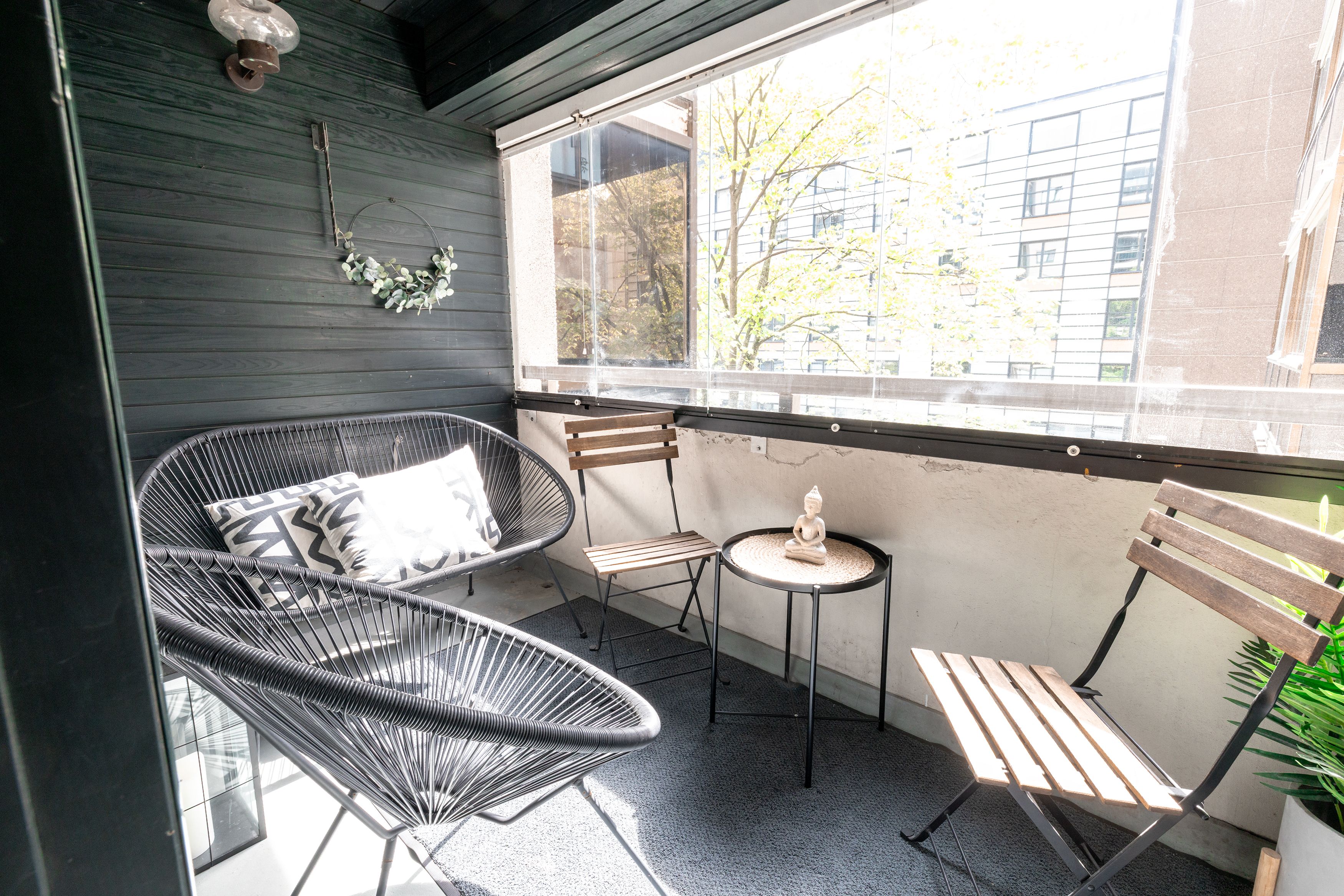 A balcony with a wicker chair, a small table, and a bench.