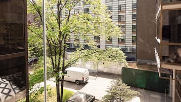 A view of a courtyard with a tree, a parked van, and a building with a grid-like facade.