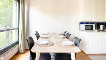 Comedor con una mesa dispuesta para seis, sillas y vistas al exterior a través de un ventanal.