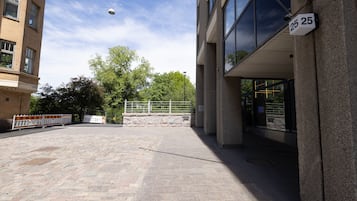 A paved courtyard with a building entrance, a street lamp, and a tree.