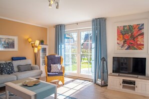 Un salon avec un canapé, un fauteuil et un meuble pour la télévision.
