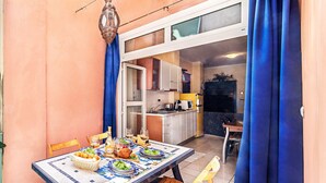 Een terras met eethoek voor twee personen, een hanglamp en uitzicht op de keuken.