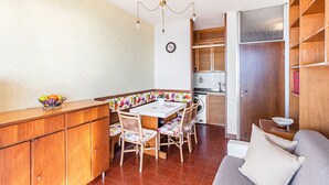 Une cuisine compacte avec un coin repas, des meubles en bois, un lave-linge et un canapé.