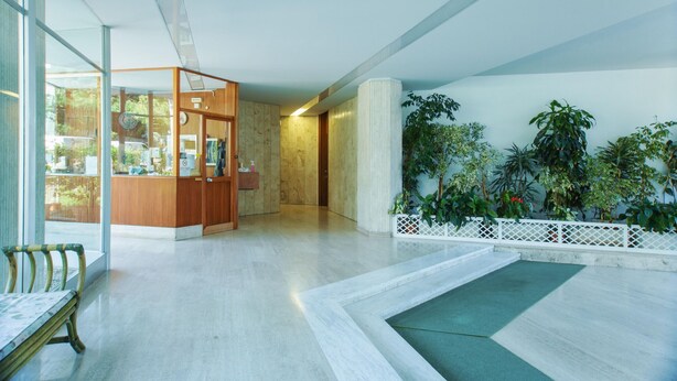 A spacious lobby with a wooden reception desk, a bench, and a white decorative railing. - Imperatrice Apartment by Wonderful Italy (Sanremo)