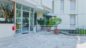 A modern building with a glass entrance, potted plants, and a stone-paved courtyard. - Imperatrice Apartment by Wonderful Italy (Sanremo)