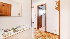A hallway with a wooden door, a white wall, and a tiled floor.