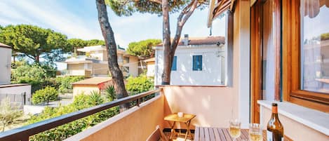 A balcony with a wooden table, two chairs, and a bottle of wine.