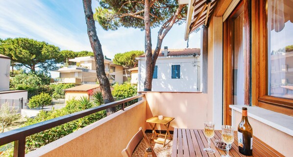 Un balcon avec une table en bois, deux chaises et une bouteille de vin.