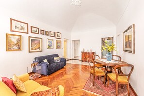 Un salon comprenant un canapé, des fauteuils, une table à manger et des œuvres d’art accrochées aux murs.