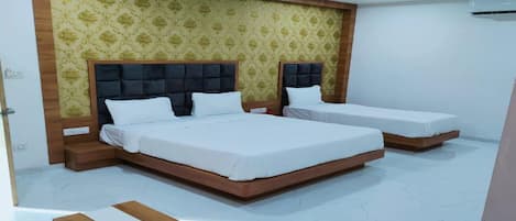 Un dormitorio con dos camas, un banco de madera, un ventilador de techo y un papel tapiz estampado.