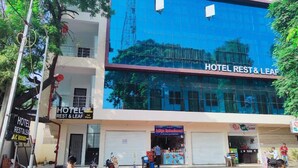 A hotel named HOTEL REST & LEAF with a modern glass facade, a ground floor with a visible restaurant, and a sign indicating A/C rooms.