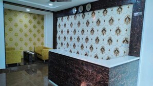 A reception area with a marble counter, patterned wallpaper, and a ceiling fan.
