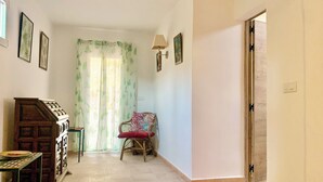 A hallway with a wooden cabinet, a chair with a red cushion, a patterned rug, and a door. - Spacious Andalusian Country House with Pool Near Cabo de Gata (Níjar)