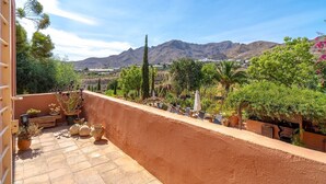 A terrace with potted plants, outdoor furniture, and a view of mountains. - Spacious Andalusian Country House with Pool Near Cabo de Gata (Níjar)