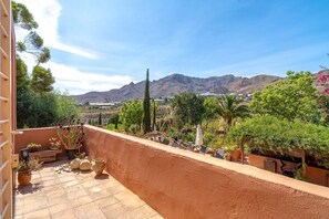 Eine Terrasse mit Blumentöpfen, Gartenmöbeln und Blick auf Berge.