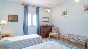 A bedroom with two beds, a dresser, a chair, a bench, and a window with curtains. - Spacious Andalusian Country House with Pool Near Cabo de Gata (Níjar)