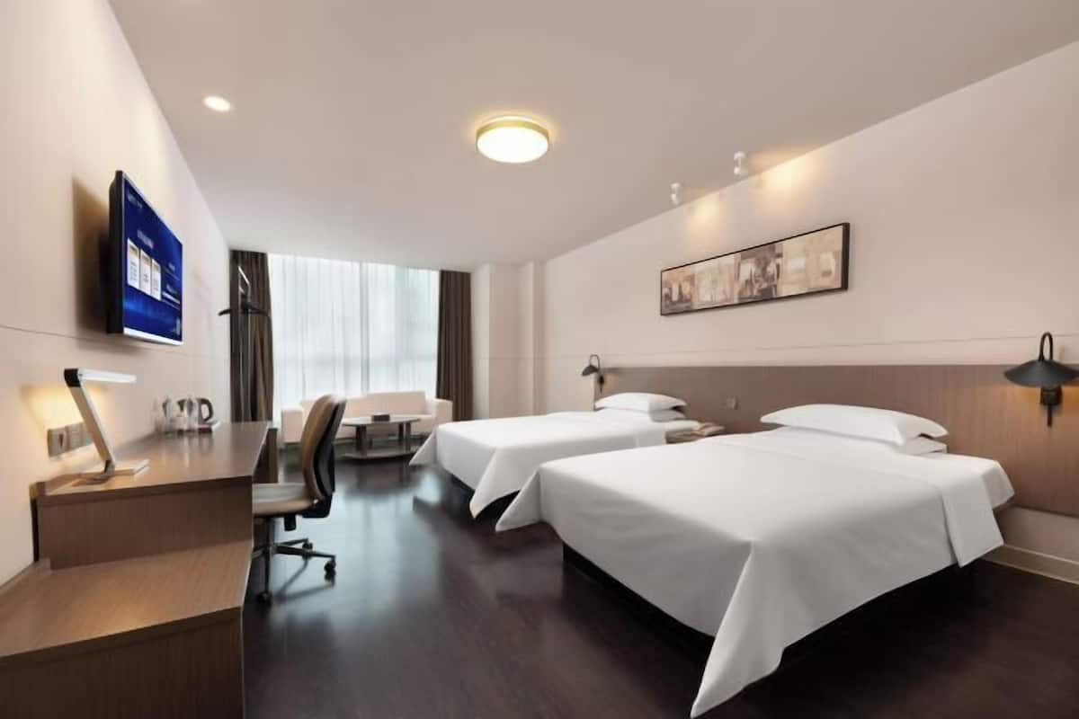 Habitació d'hotel amb dos llits, un escriptori, una cadira, un televisió de pantalla plana i un quadre a la paret.