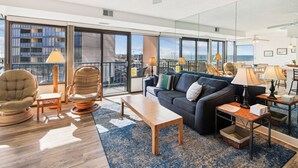 Een ruime woonkamer met een bank, stoelen, een salontafel en een balkon met uitzicht.