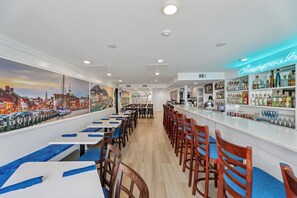 Angolo bar con un neon che riporta la scritta 'Chesapeake Bay' e un murale raffigurante un panorama urbano.