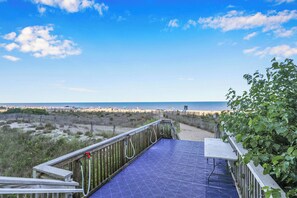 A wooden deck with a metal railing overlooking a beach.