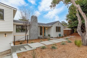 A modern house with a concrete staircase, a small front porch, and a garden with mulch and plants.