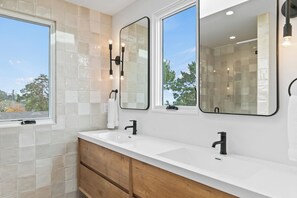 Een moderne badkamer met twee wasbakken, een grote spiegel en een raam.