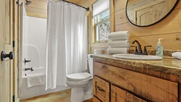 Een bad/douchecombinatie, een haardroger, handdoeken, zeep